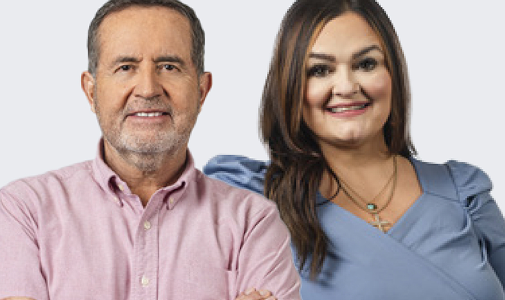 A Latino man with short dark hair smiles and is sitting next to a Latino woman with long, brown hair who is also smiling.